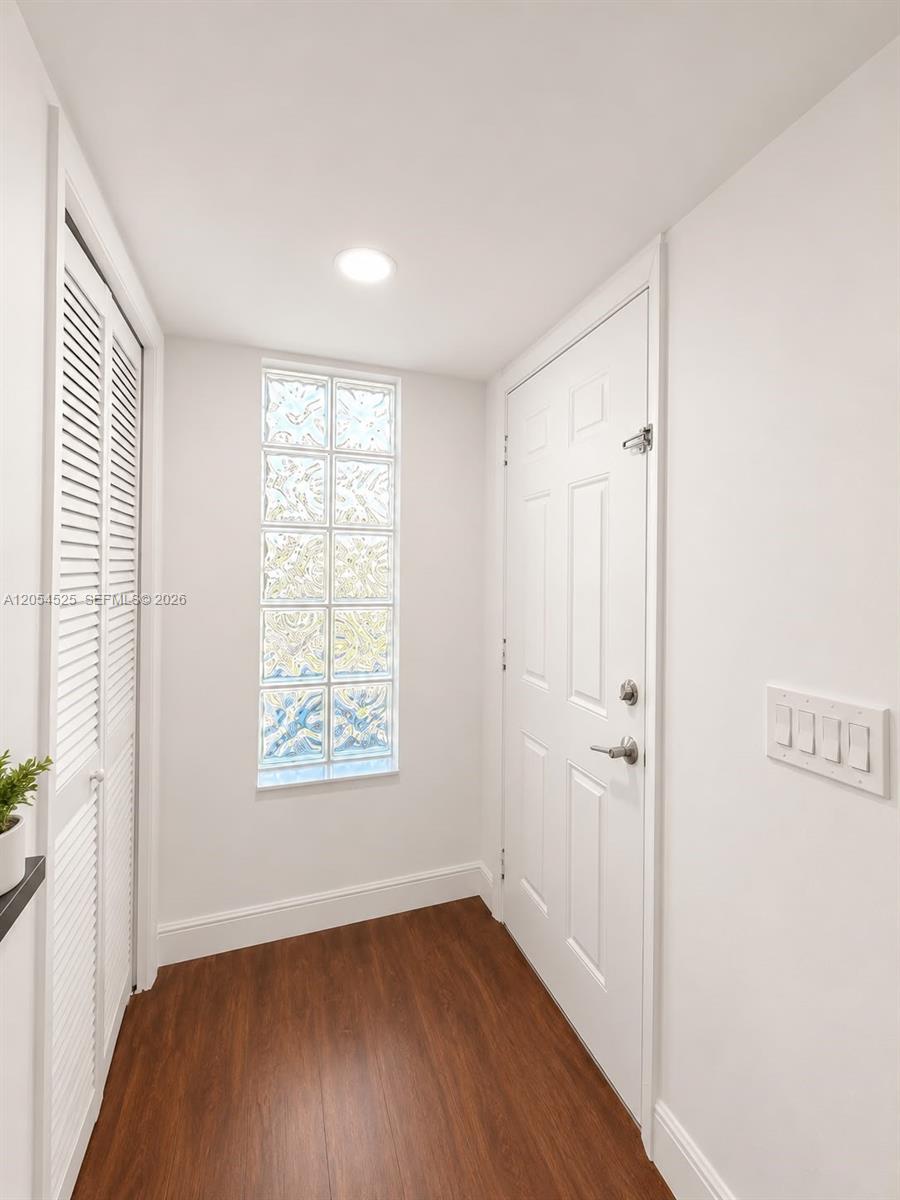 A white entryway features a glass block window, a white door, and wood-look flooring — 16571 Blatt Blvd # 203, Weston FL 33326, WESTON, FL