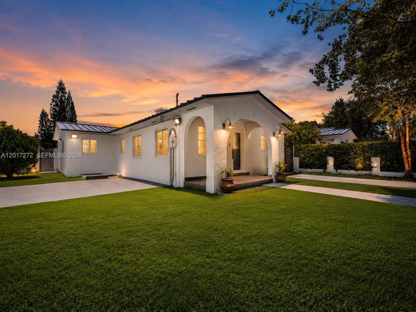 A white single-story house with a covered arched entryway sits on a grassy lawn — 1900 SW 24th St, Miami FL 33145, MIAMI, FL