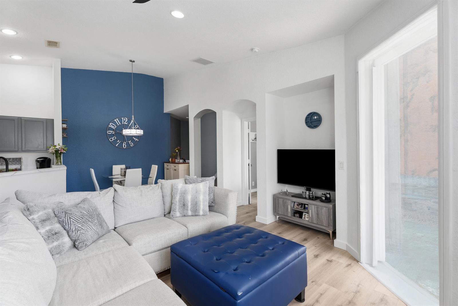 A living room features a blue accent wall, a sectional sofa, and a blue ottoman — 1706 Carvelle Drive, Riviera Beach FL 33404, RIVIERA BEACH, FL