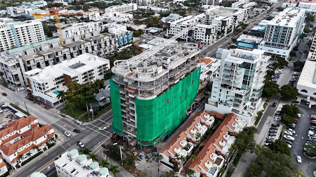 An aerial view shows a multi-story building under construction wrapped in green safety netting — 290 COCOANUT AVENUE UNIT 604, SARASOTA, FL