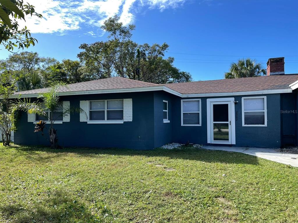 A single-story house with dark blue exterior walls, white trim, and a brick chimney — 2302 CONTINENTAL BOULEVARD, ORLANDO, FL
