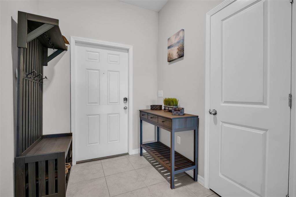 An entryway features a dark wood hall tree, a console table, and a white door — 8512 REEDVILLE STREET, NEW PORT RICHEY, FL