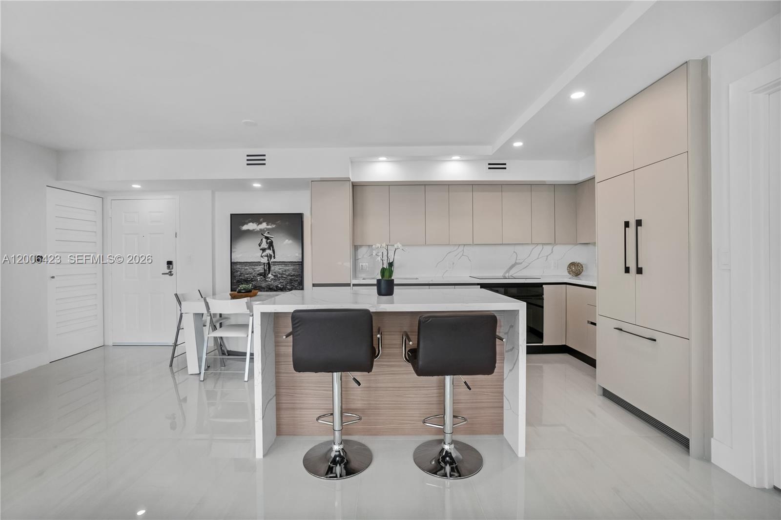 A modern kitchen features a marble-topped island, two black bar stools, and light-colored cabinetry — 1155 Brickell Bay Dr # 2003, Miami FL 33131, MIAMI, FL