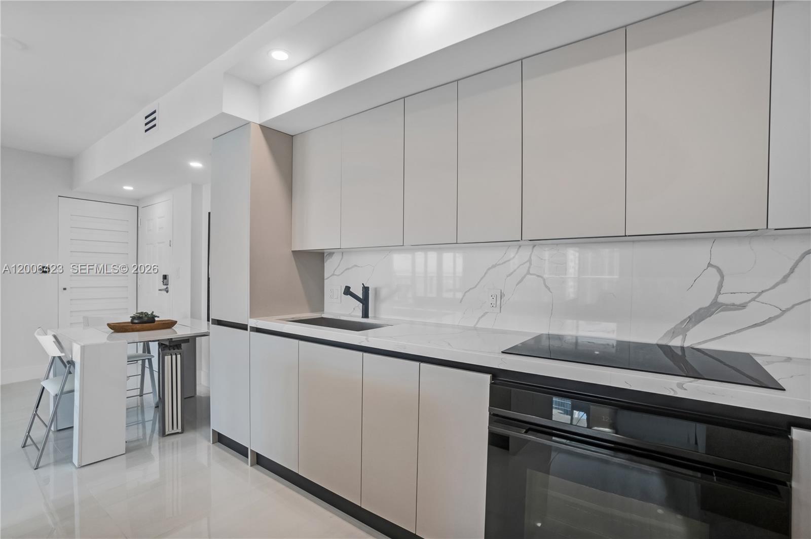 A modern kitchen features light gray flat-panel cabinets, white marble countertops, and a black oven — 1155 Brickell Bay Dr # 2003, Miami FL 33131, MIAMI, FL