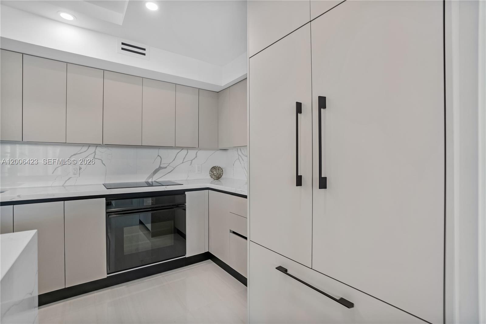 A modern kitchen features light gray cabinetry, marble-patterned backsplashes, and black hardware — 1155 Brickell Bay Dr # 2003, Miami FL 33131, MIAMI, FL