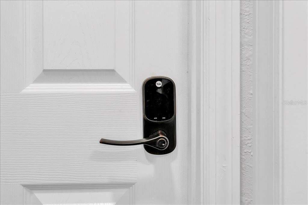 A white door features a dark bronze Yale smart lock with a lever handle — 2402 W FIG STREET, TAMPA, FL