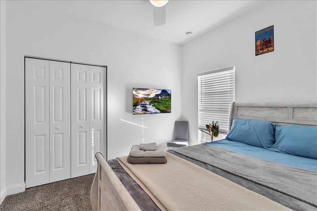 A bedroom features a bed with blue bedding, a wall-mounted television, and a white closet — 2402 W FIG STREET, TAMPA, FL