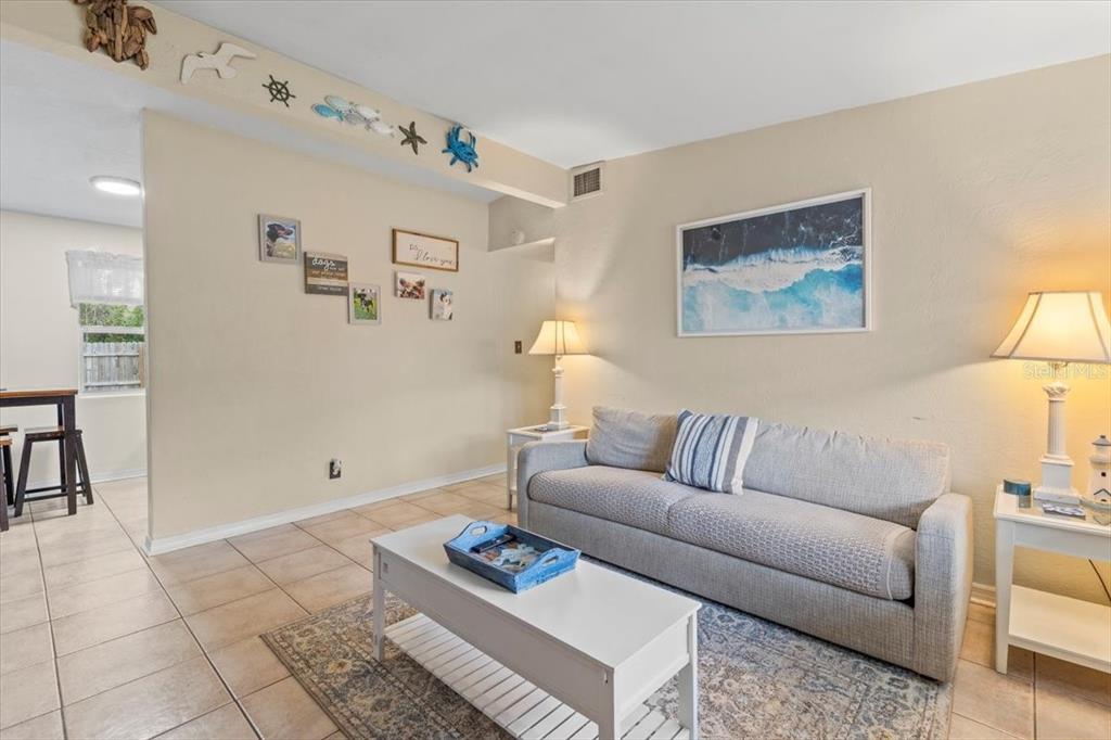 A living room features a gray sofa, a white coffee table, and coastal-themed wall decor — 450 CARD AVENUE, HOLLY HILL, FL