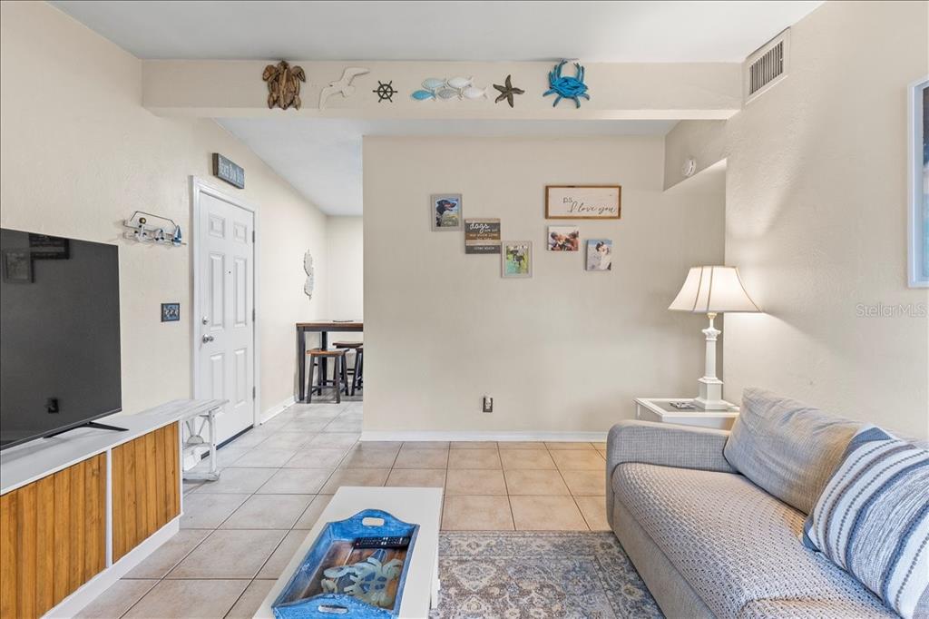 A living room features tile flooring, a sofa, a television, and coastal wall decor — 450 CARD AVENUE, HOLLY HILL, FL