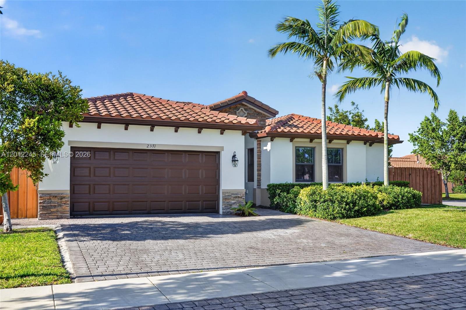 A single-story house with a brown garage door, tiled roof, and two palm trees — 2371 SE 1st Ct, Homestead FL 33033, HOMESTEAD, FL