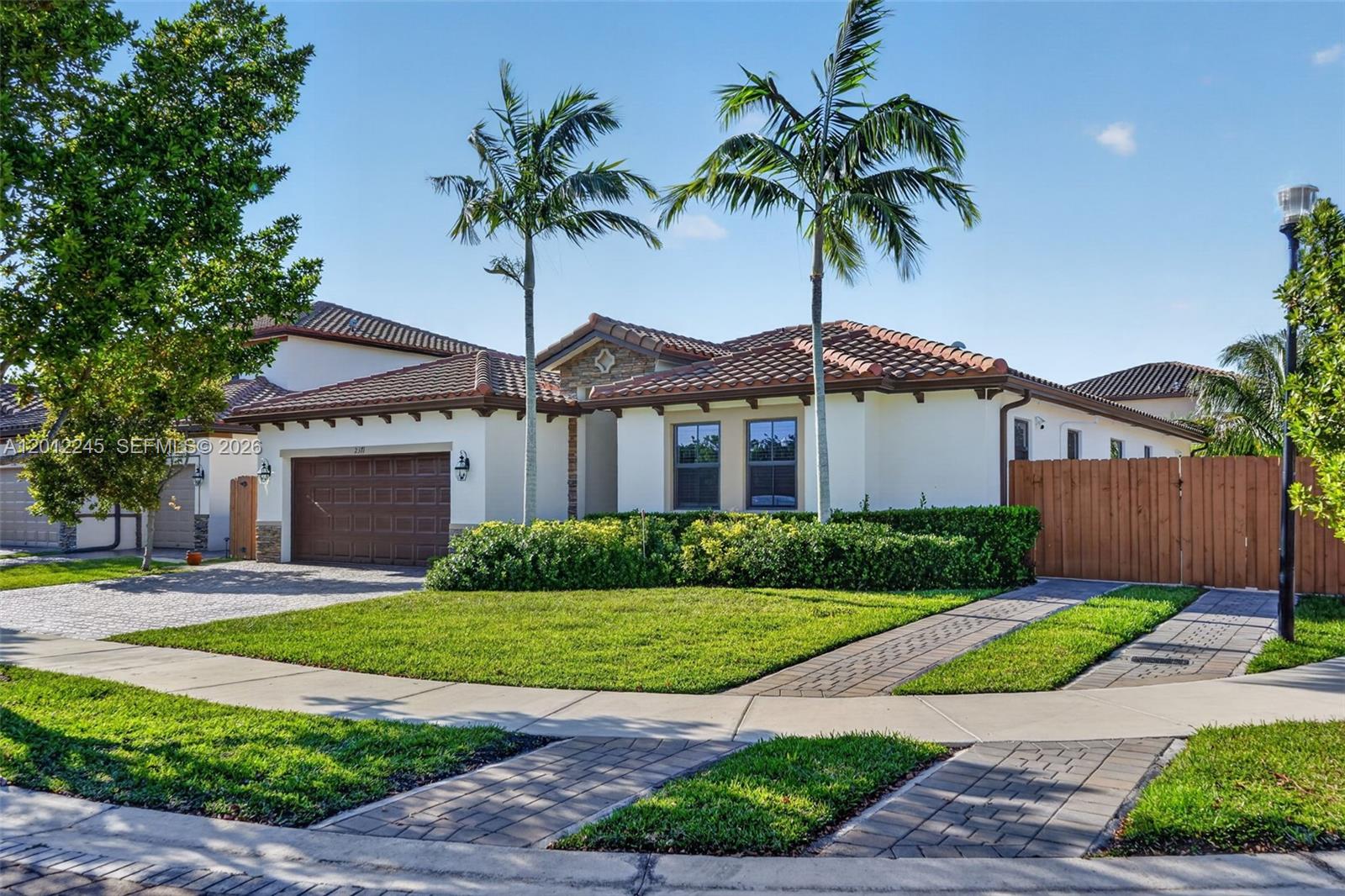 A single-story house with a brown garage, tile roof, and two palm trees in front — 2371 SE 1st Ct, Homestead FL 33033, HOMESTEAD, FL
