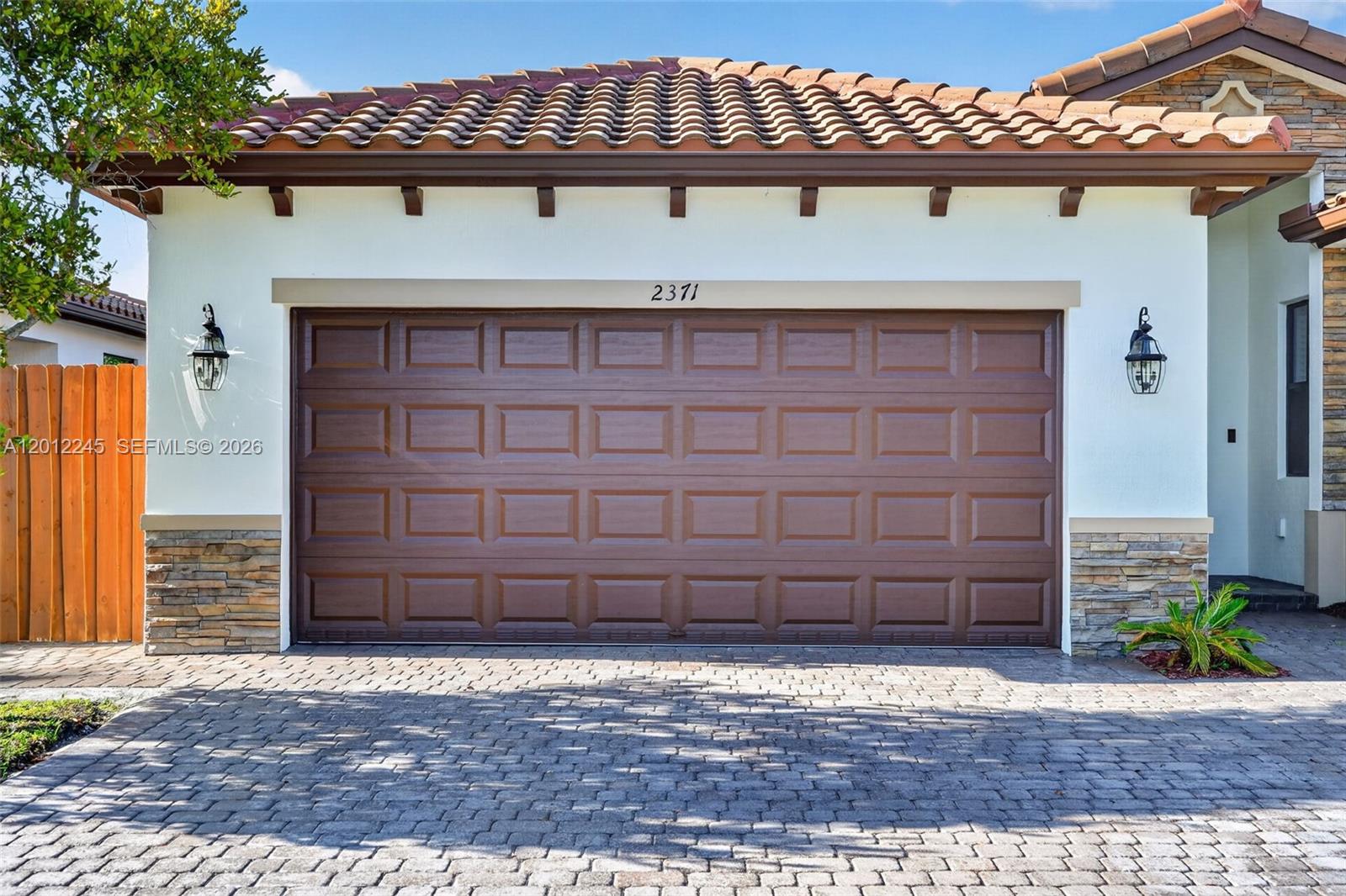 A brown garage door with a tiled roof and stone accents on a paved driveway — 2371 SE 1st Ct, Homestead FL 33033, HOMESTEAD, FL