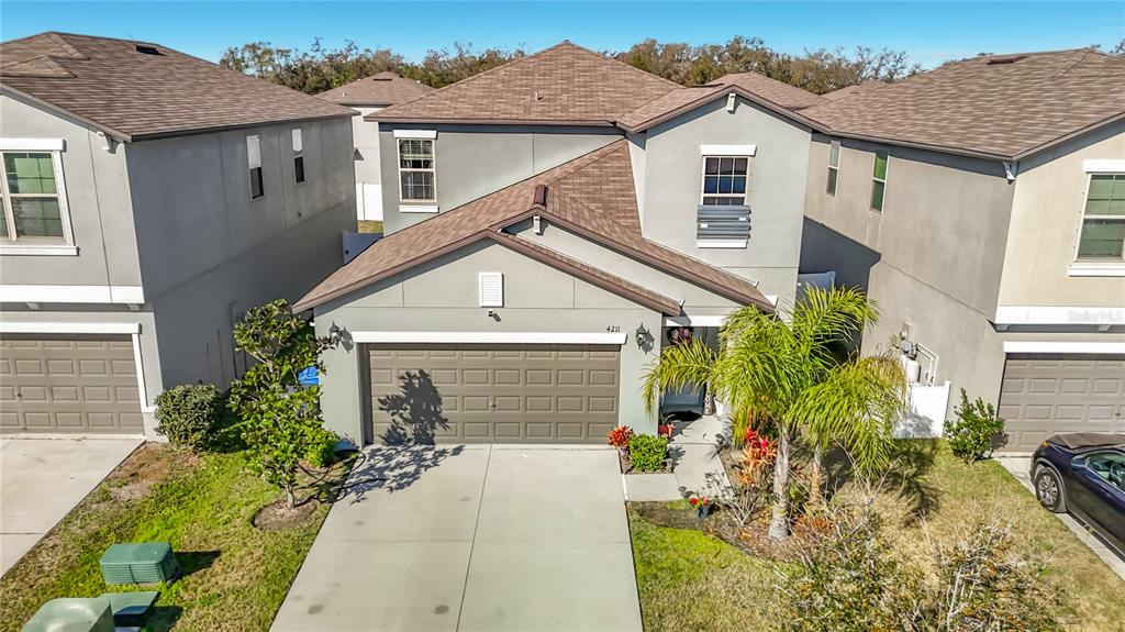An exterior view of a two-story suburban house with a gray facade and attached garage — 4211 ROMANO BUSCIGLIO STREET, TAMPA, FL