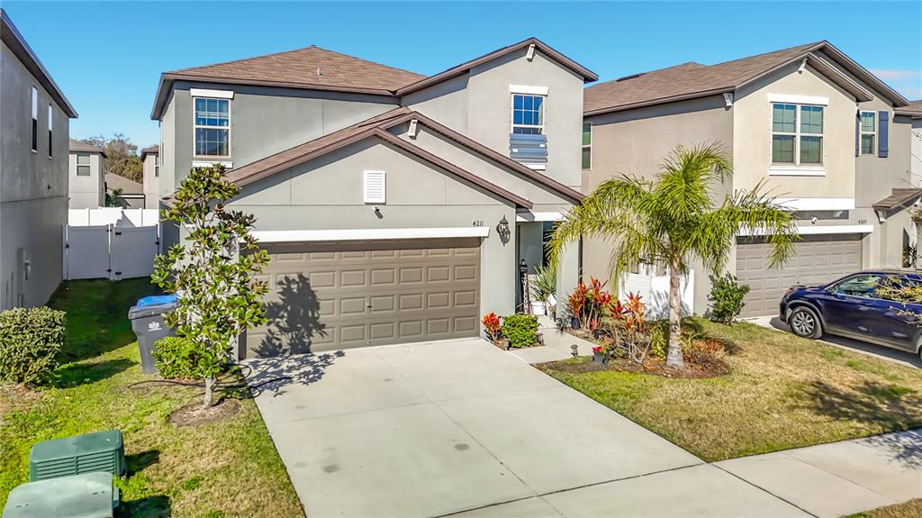 A two-story suburban house with a gray stucco exterior, a two-car garage, and a driveway — 4211 ROMANO BUSCIGLIO STREET, TAMPA, FL