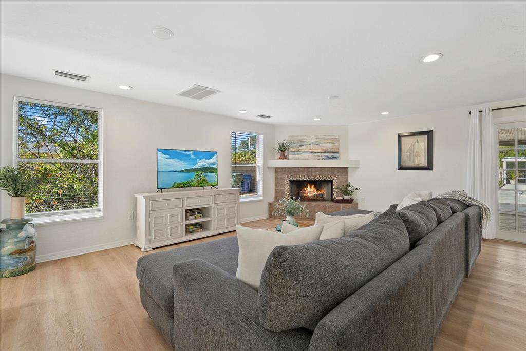 A living room features a fireplace, a large gray sectional sofa, and light wood flooring — 5868 DENISON DRIVE, VENICE, FL