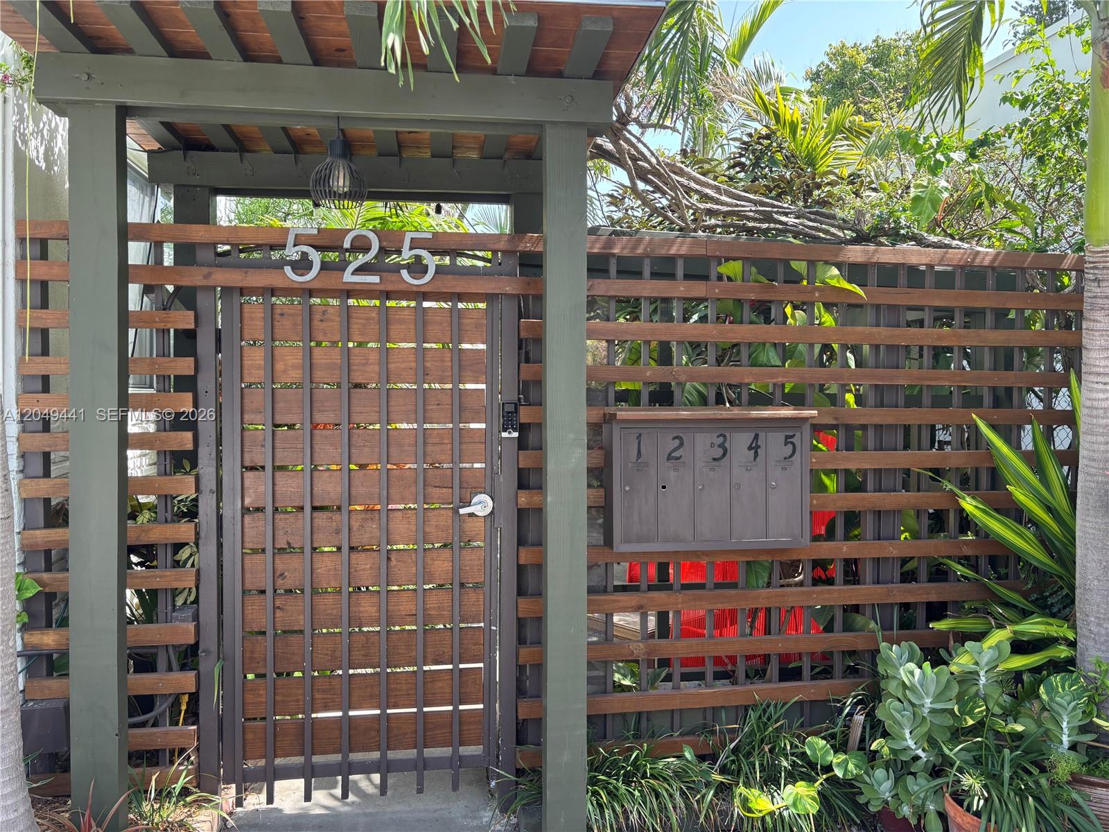 A wooden gate with a house number and a wall-mounted mailbox sits under a pergola — 525 NE 63rd St # 4, Miami FL 33138, MIAMI, FL