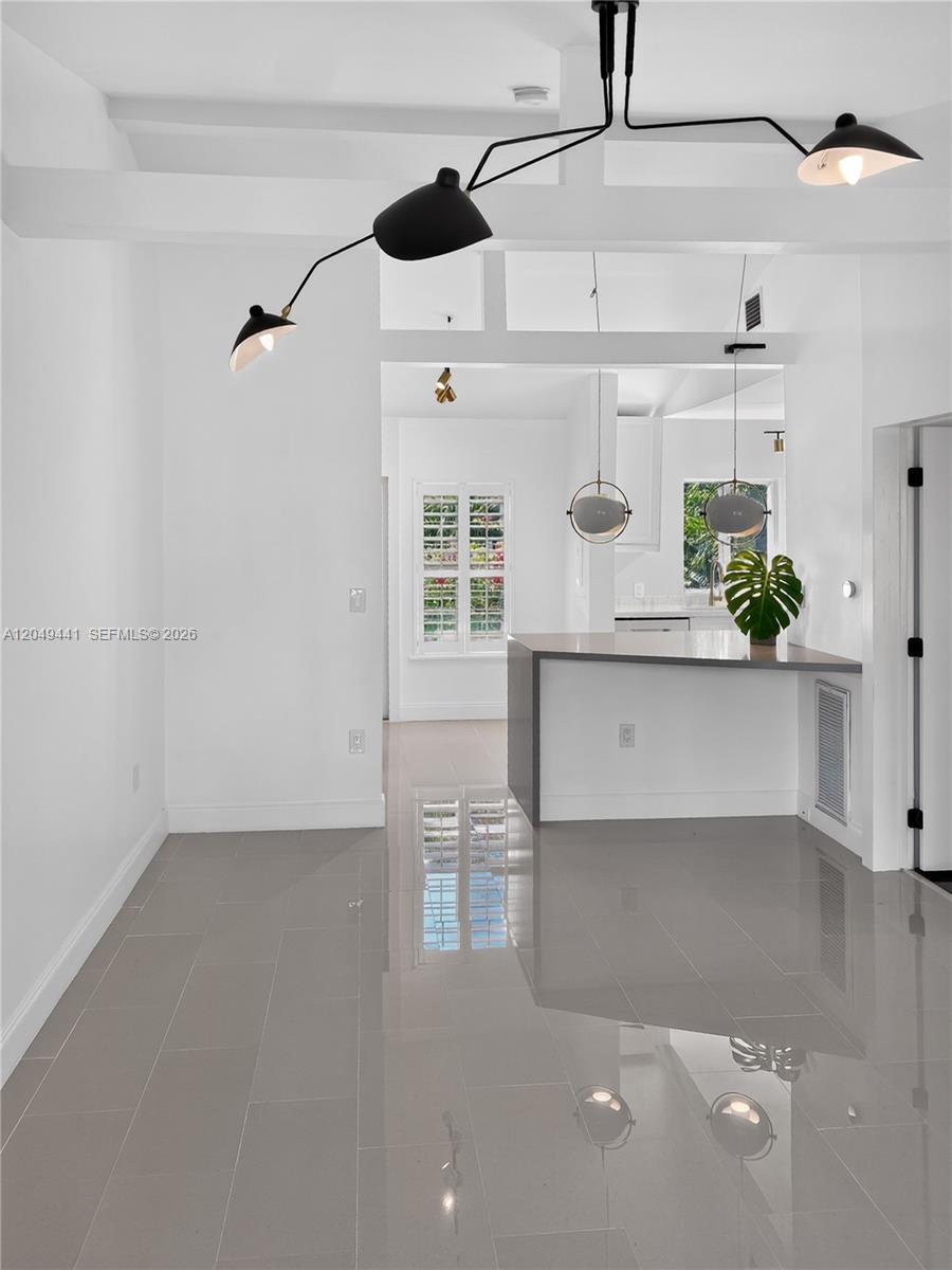 A modern living area features white walls, glossy gray tile floors, and a geometric chandelier — 525 NE 63rd St # 4, Miami FL 33138, MIAMI, FL