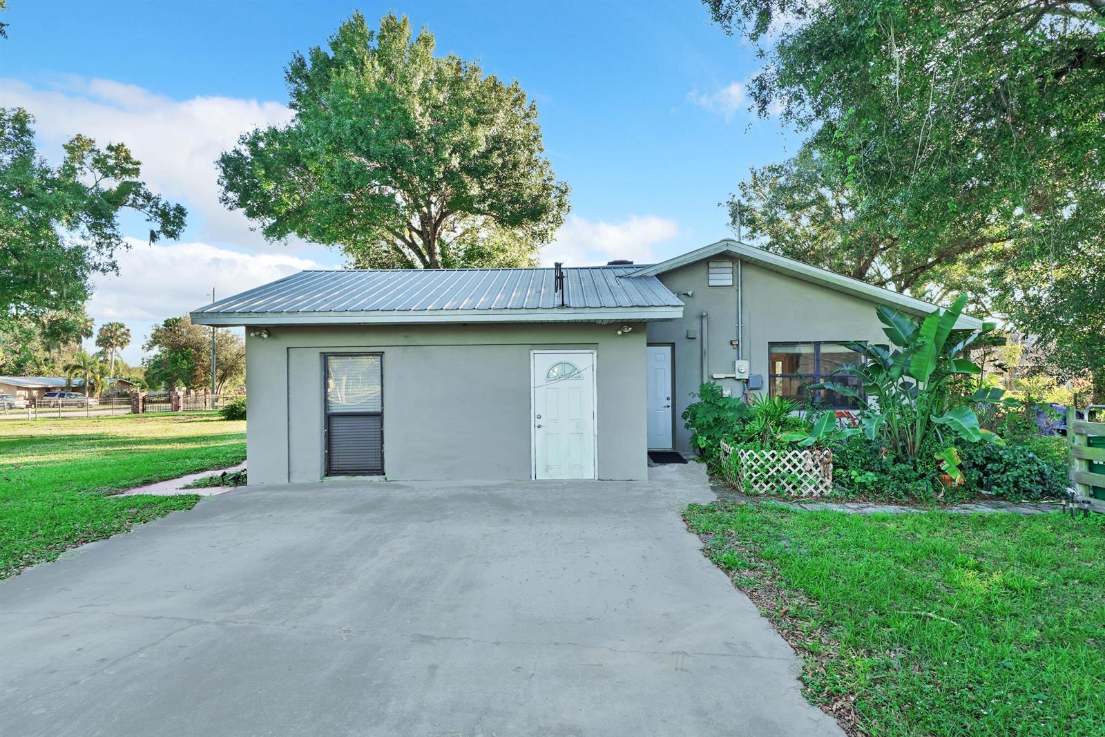 A single-story house with a metal roof, concrete driveway, and green lawn — 1031 SW 24th Avenue, Okeechobee FL 34974, OKEECHOBEE, FL