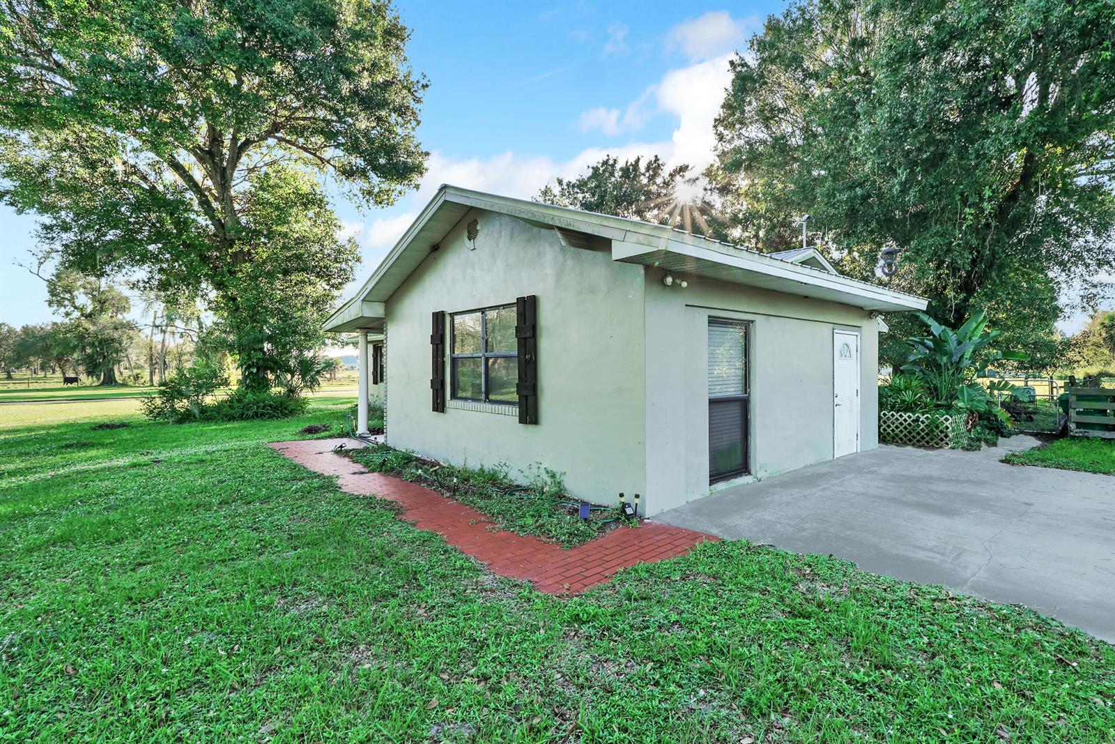 A small, light-colored detached building with a red brick walkway and a concrete driveway — 1031 SW 24th Avenue, Okeechobee FL 34974, OKEECHOBEE, FL