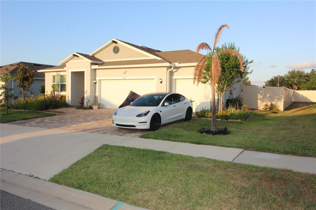 A white Tesla is parked in the driveway of a single-story suburban house — 9449 SANDERS PARK PLACE, SEFFNER, FL