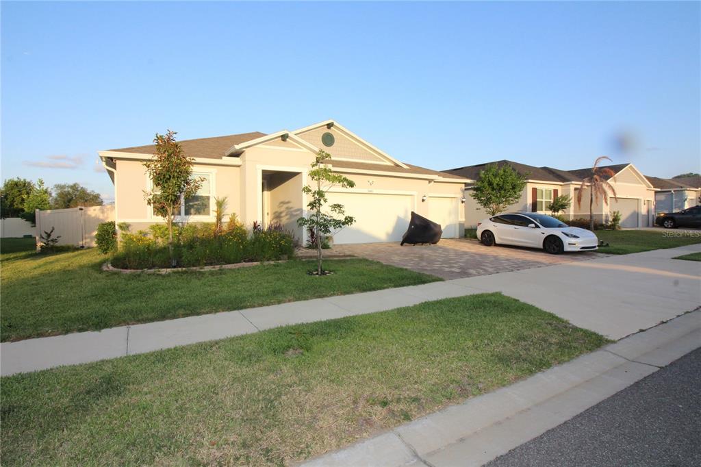 A single-story suburban house with a beige exterior, a paved driveway, and a white car — 9449 SANDERS PARK PLACE, SEFFNER, FL
