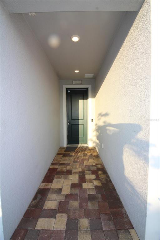 A covered entryway features a dark door, recessed lighting, and a multicolored paver floor — 9449 SANDERS PARK PLACE, SEFFNER, FL