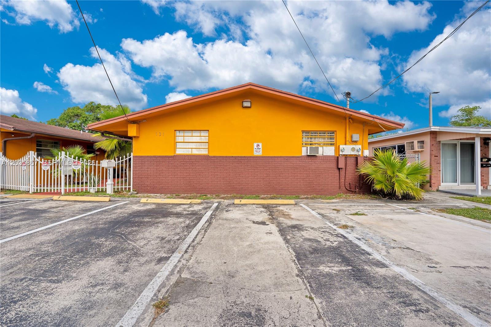 A yellow and brown exterior of a single-story building with a paved parking lot — 129-131 SE 5th St, Hallandale Beach FL 33009, HALLANDALE BEACH, FL