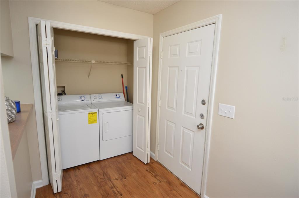 A laundry closet with a washer and dryer sits next to a white exterior door — 11901 4TH STREET N UNIT 10105, ST PETERSBURG, FL