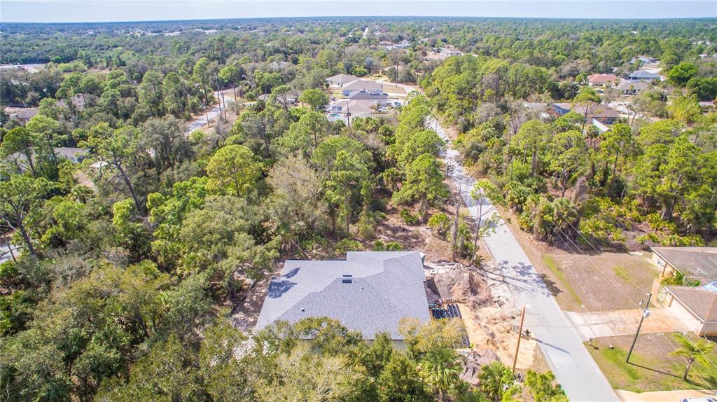 An aerial view shows a house under construction surrounded by dense trees and a road — DUNDEE AVENUE, NORTH PORT, FL