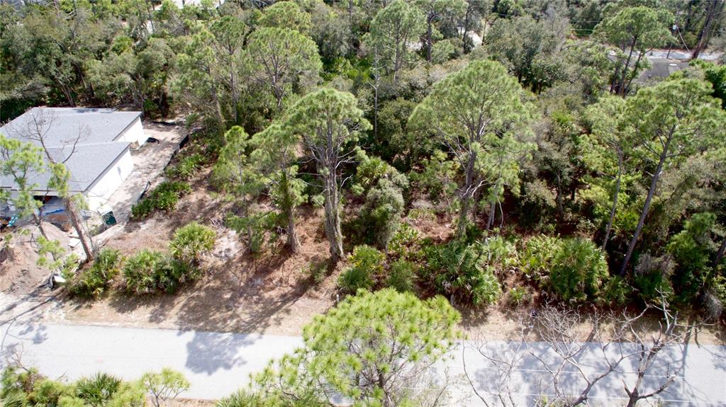 An aerial view shows a wooded residential lot next to a house under construction — DUNDEE AVENUE, NORTH PORT, FL