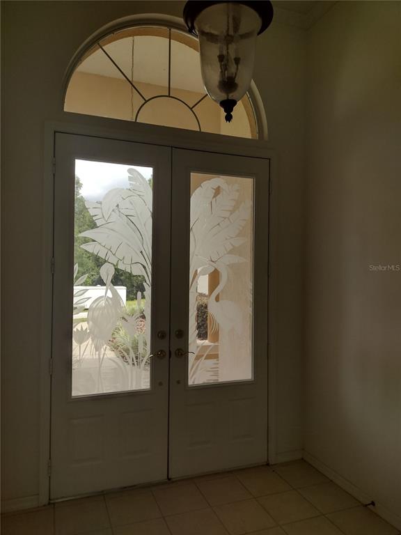 A white double front door with etched glass panels featuring tropical birds and foliage — 8941 SW 191ST CIRCLE, DUNNELLON, FL