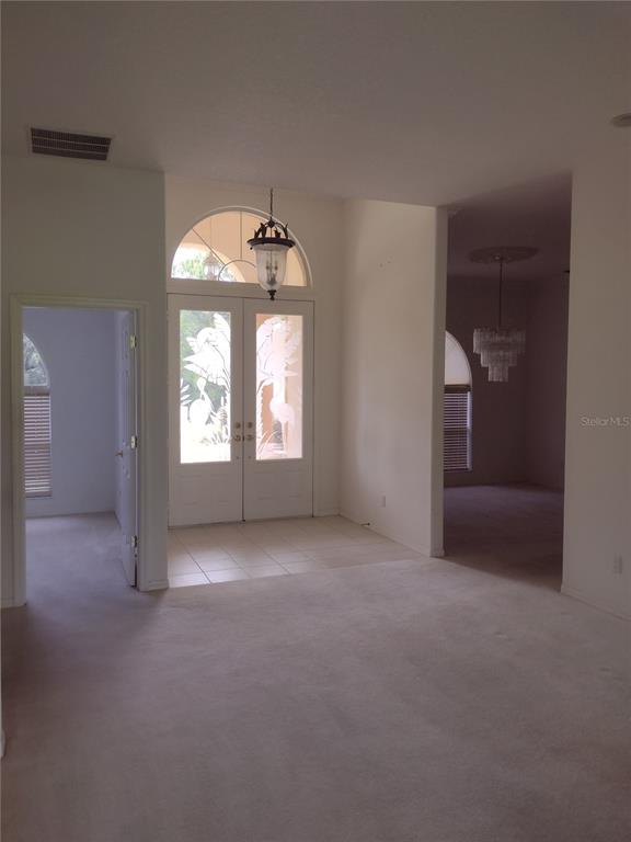 An entryway with a double door, arched transom window, tile flooring, and carpeted living area — 8941 SW 191ST CIRCLE, DUNNELLON, FL
