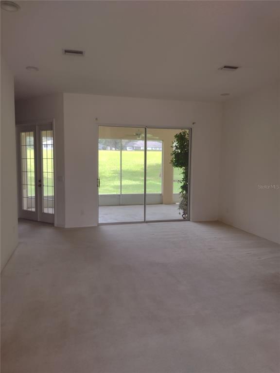 An interior view of a carpeted living area featuring sliding glass doors leading to a lanai — 8941 SW 191ST CIRCLE, DUNNELLON, FL