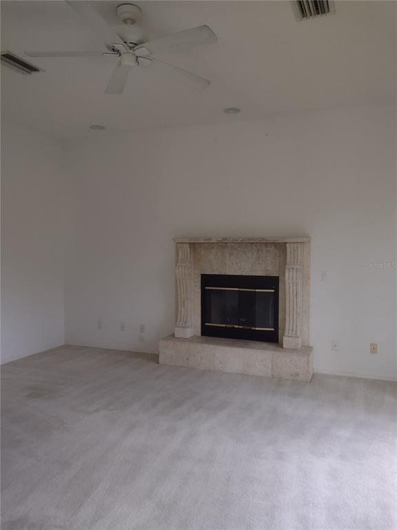 A living room features a beige carpet, a ceiling fan, and a stone fireplace — 8941 SW 191ST CIRCLE, DUNNELLON, FL