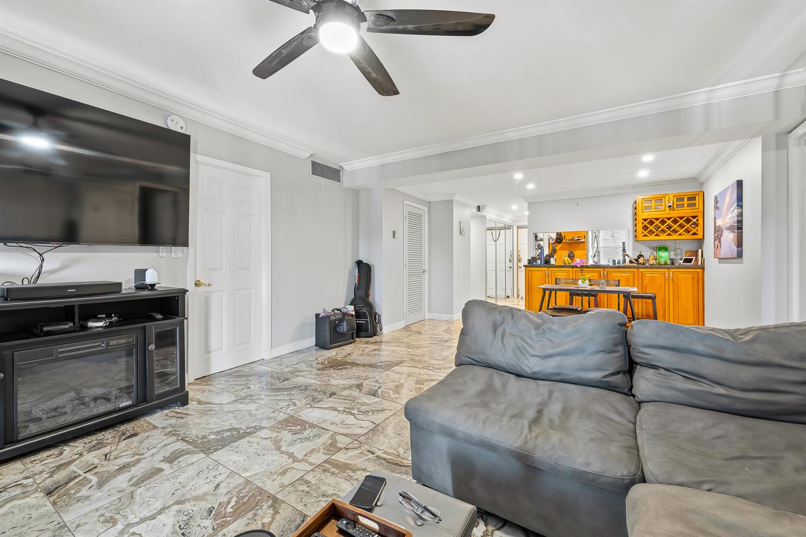 A living room features a grey sectional sofa, marble-patterned tile floors, and an open kitchen — 1319 E Hillsboro Boulevard # 208, Deerfield Beach FL 33441, DEERFIELD BEACH, FL