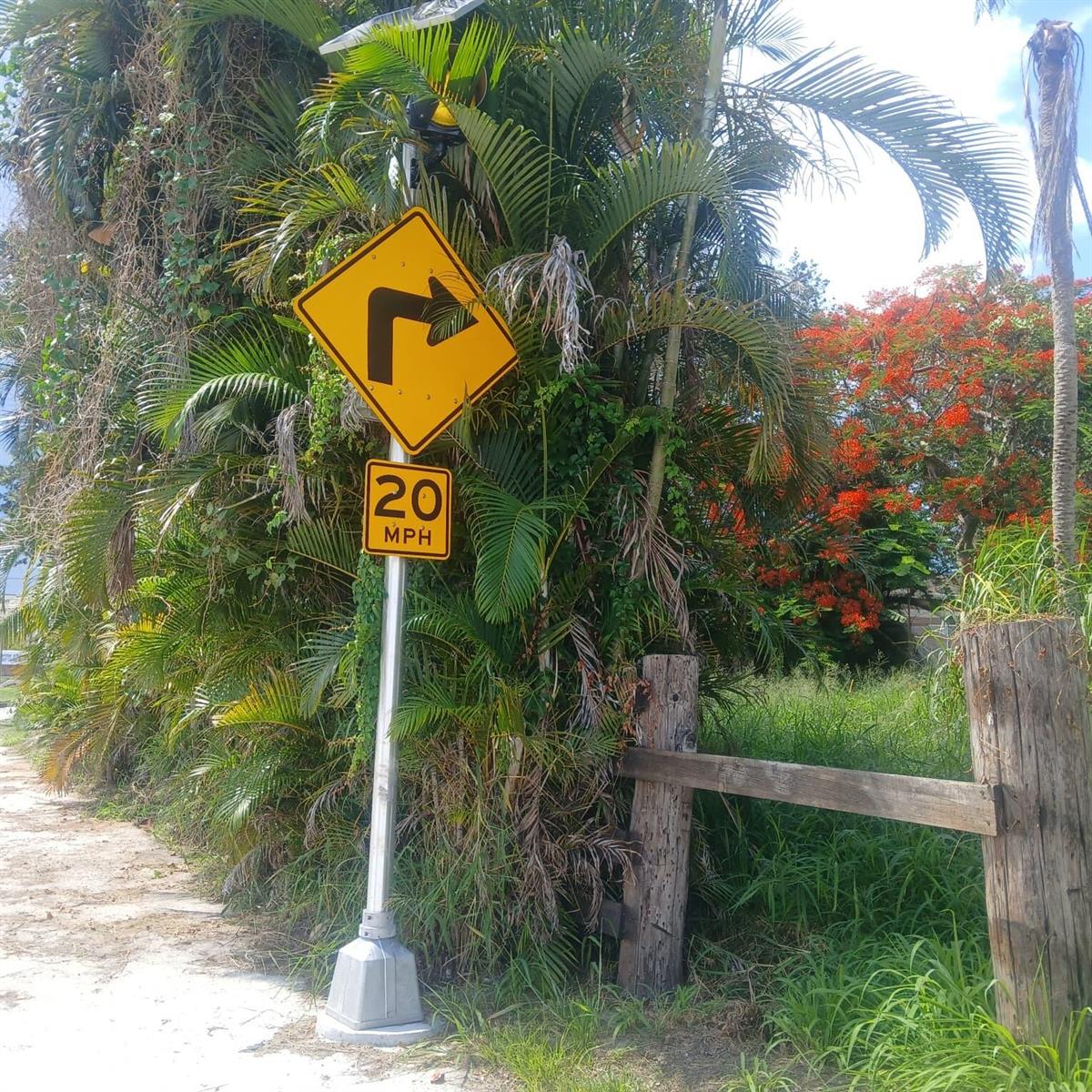 A yellow road sign indicating a sharp right turn with a 20 MPH speed limit — 37121 E Main Street, Canal Point FL 33438, CANAL POINT, FL