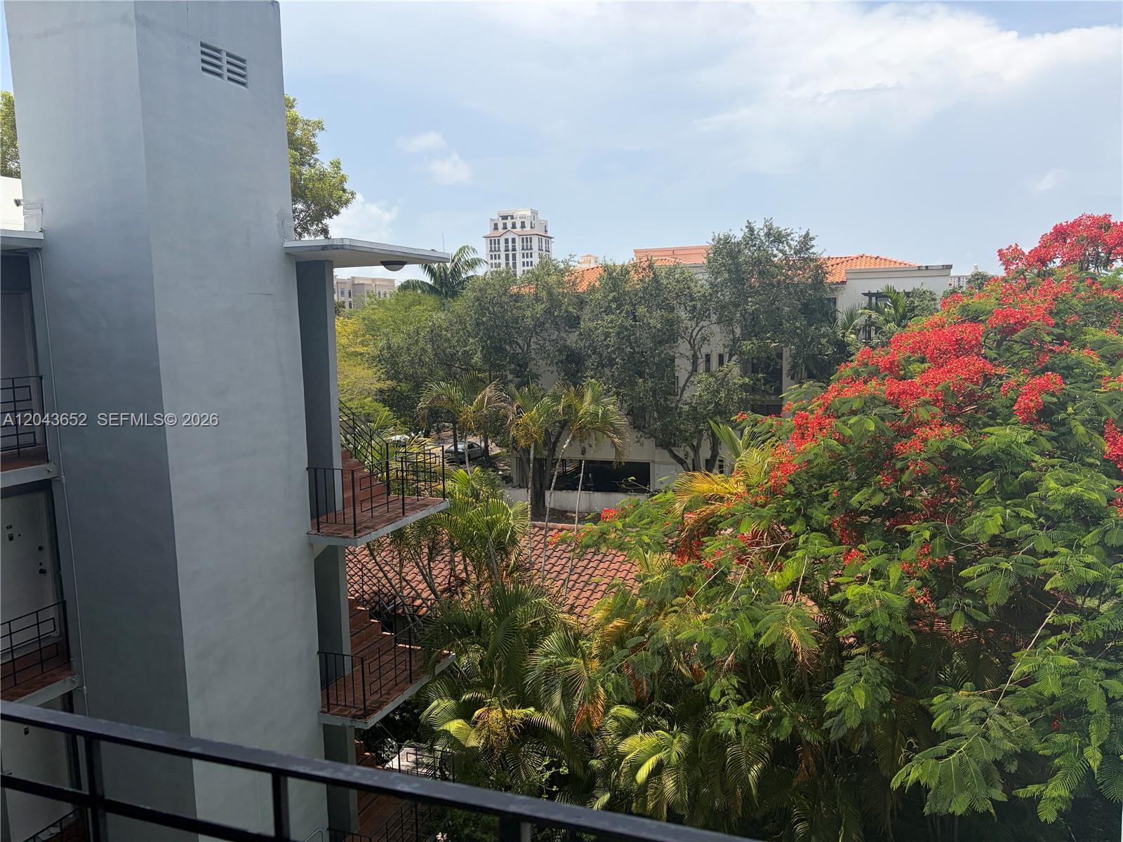 An exterior view shows a multi-story building with balconies overlooking trees and a red-tiled roof — 820 Salzedo St # 405, Coral Gables FL 33134, CORAL GABLES, FL