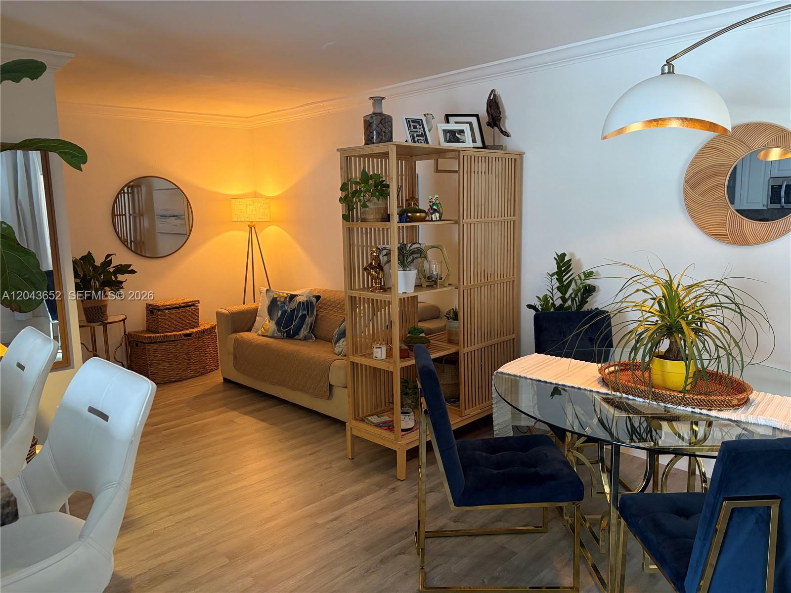 A living and dining area features wood-look flooring, a room divider, and blue velvet chairs — 820 Salzedo St # 405, Coral Gables FL 33134, CORAL GABLES, FL
