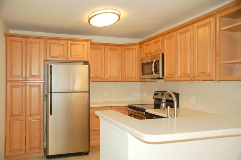 A kitchen with light wood cabinets, stainless steel appliances, and a white countertop peninsula — 1885 Palm Cove Boulevard # 203, Delray Beach FL 33445, DELRAY BEACH, FL