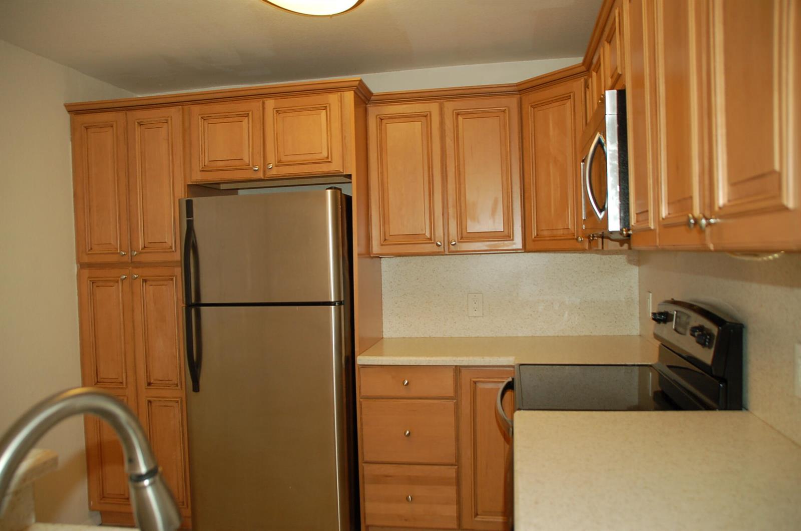 A kitchen with light wood cabinets, stainless steel appliances, and light-colored countertops — 1885 Palm Cove Boulevard # 203, Delray Beach FL 33445, DELRAY BEACH, FL