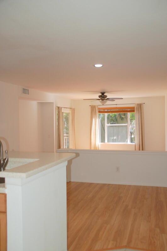 A kitchen counter overlooks a living area with light wood flooring and a ceiling fan — 1885 Palm Cove Boulevard # 203, Delray Beach FL 33445, DELRAY BEACH, FL