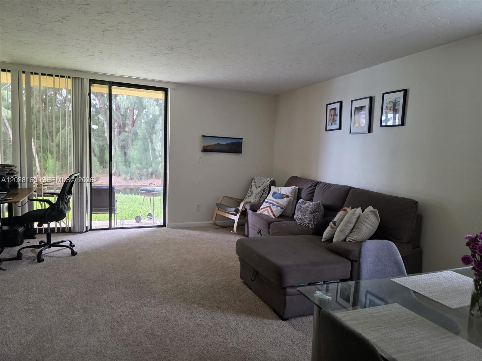 A living room features a sectional sofa, a rocking chair, and a sliding glass door — 450 Commodore Dr # 108, Plantation FL 33325, PLANTATION, FL
