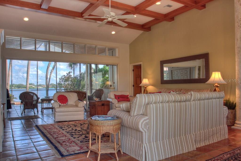 A living room features a coffered wood ceiling, striped sofa, and sliding doors to a lanai — 3434 CASEY KEY ROAD, NOKOMIS, FL