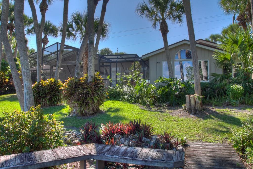 A house with a screened-in pool enclosure sits in a yard with palm trees — 3434 CASEY KEY ROAD, NOKOMIS, FL