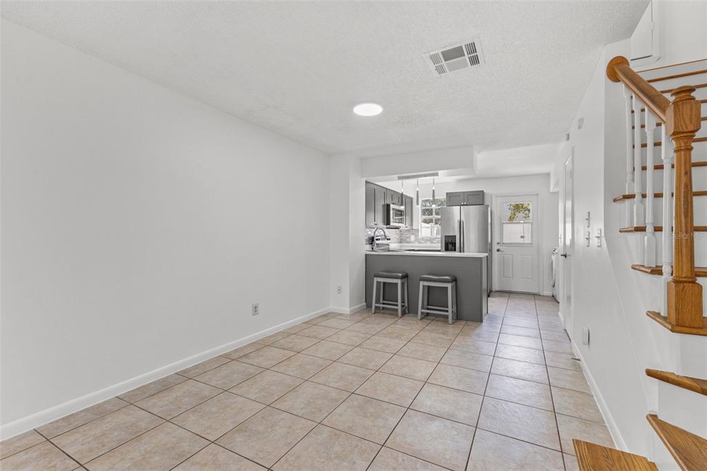 A tiled dining area leads to a kitchen with a breakfast bar and wooden stairs — 6650 121ST AVENUE UNIT 4, LARGO, FL