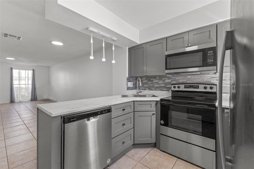 A kitchen features gray cabinets, stainless steel appliances, and a white countertop with a peninsula — 6650 121ST AVENUE UNIT 4, LARGO, FL
