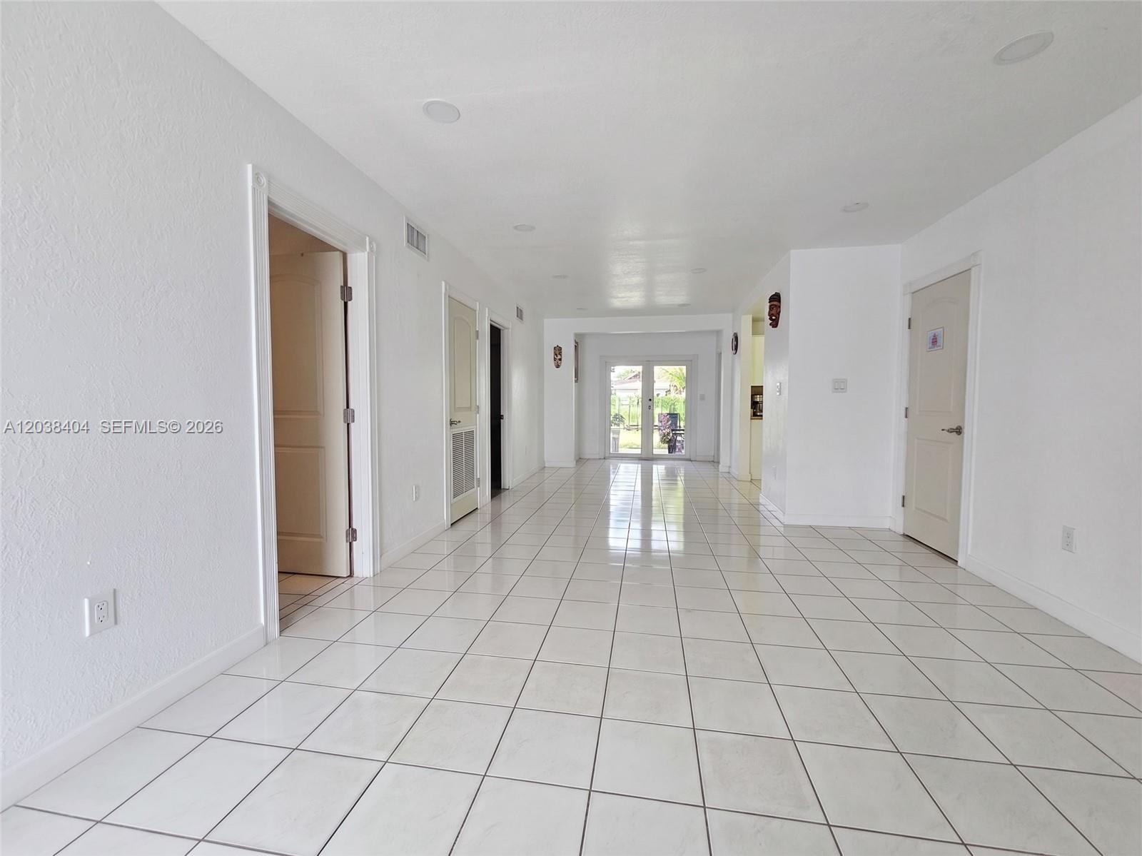 A long, white-walled hallway features light-colored tile flooring and several doorways leading to other rooms — HIALEAH, FL