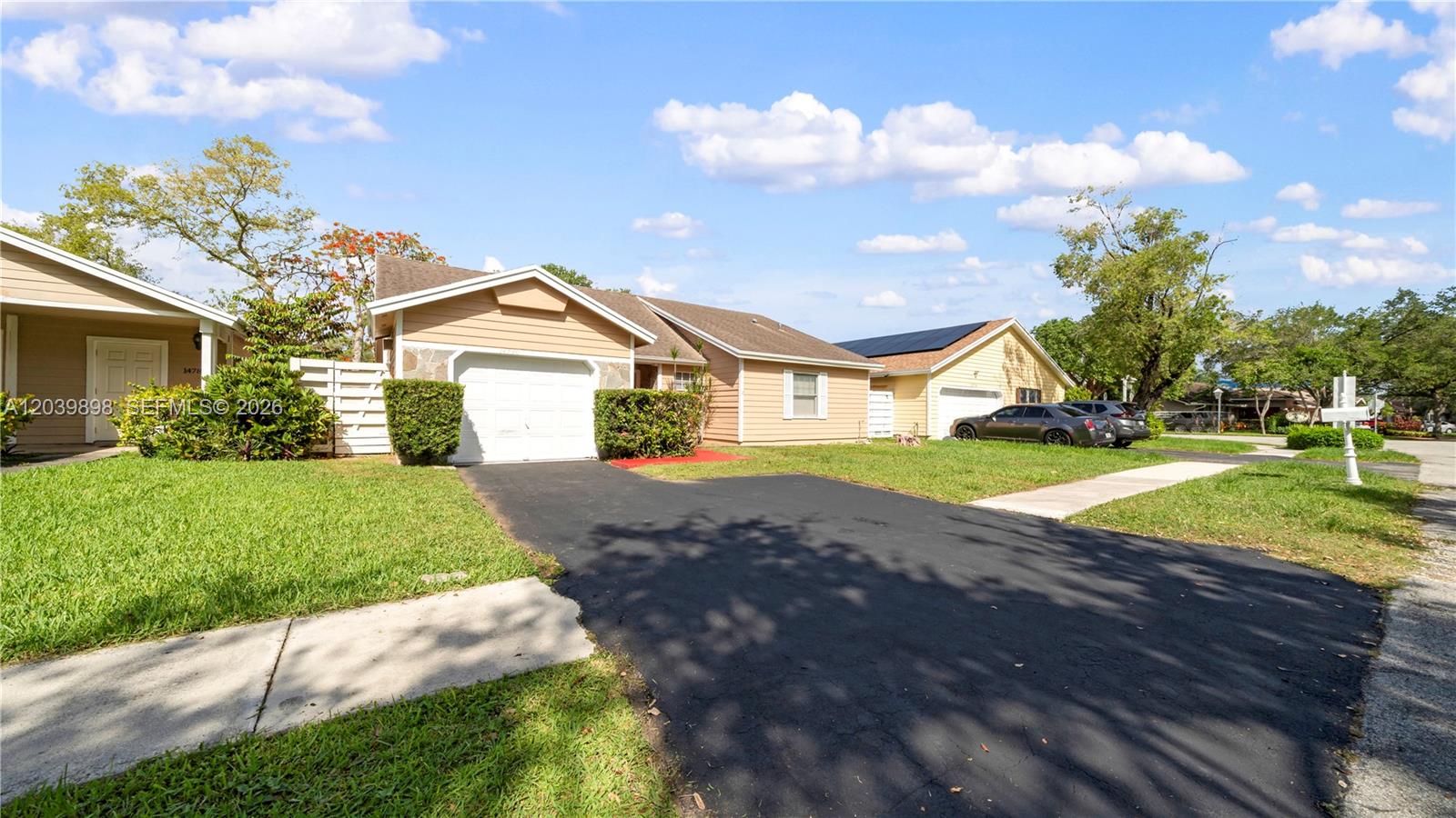 A single-story house with tan siding, a white garage door, and a paved driveway — 14780 SW 139th Ct, Miami FL 33186, MIAMI, FL