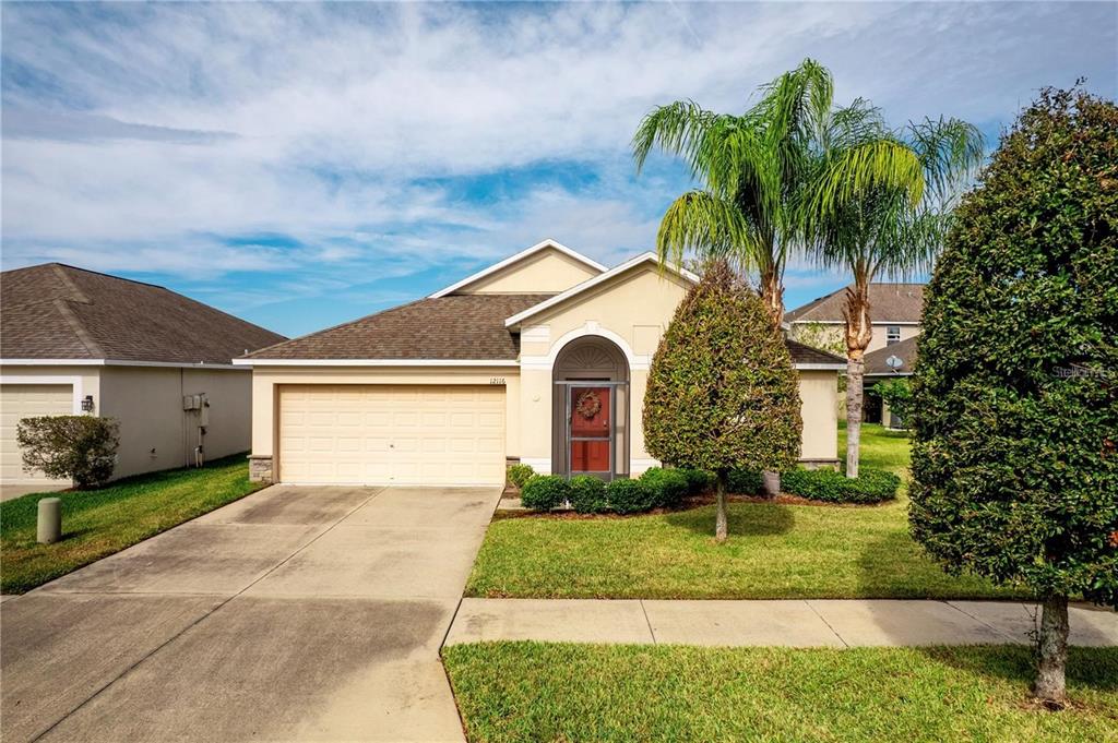 A single-story suburban house with a beige exterior, a two-car garage, and a palm tree — 12116 ECHO BASIN COVE, RIVERVIEW, FL