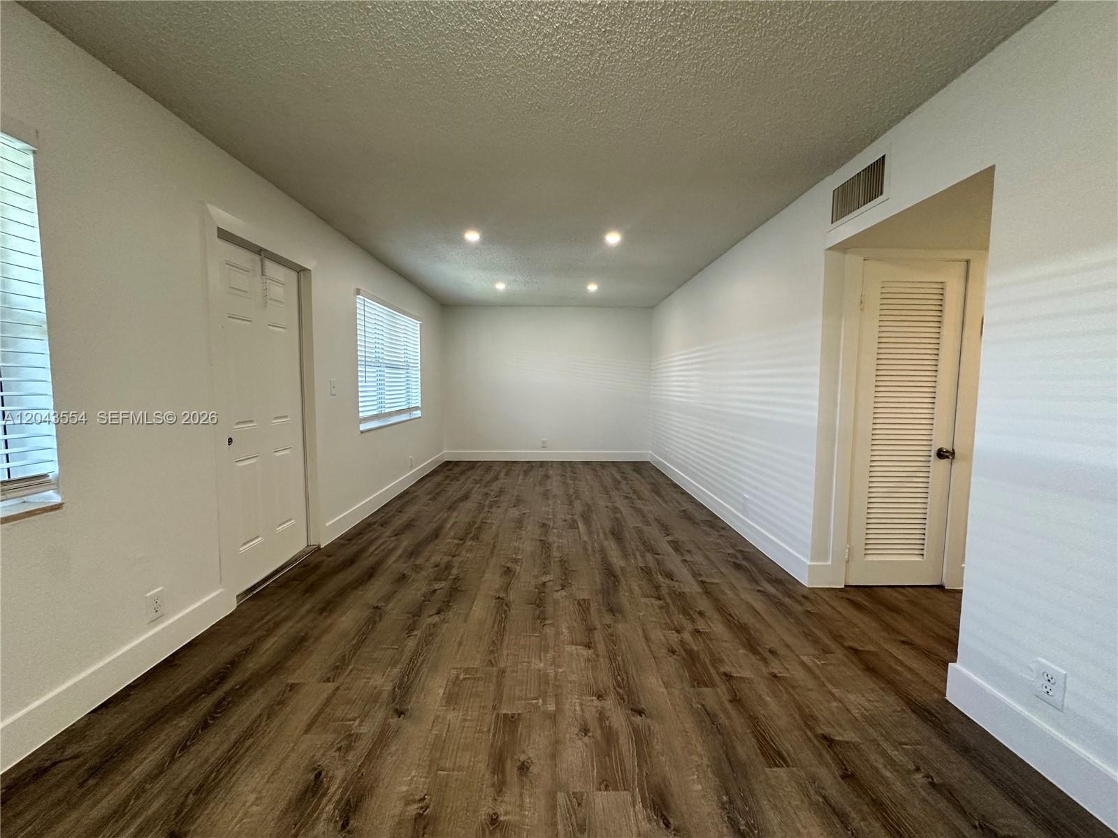 An empty room features white walls, recessed lighting, and dark wood-look flooring — 2500 Johnson St # 19, Hollywood FL 33020, HOLLYWOOD, FL
